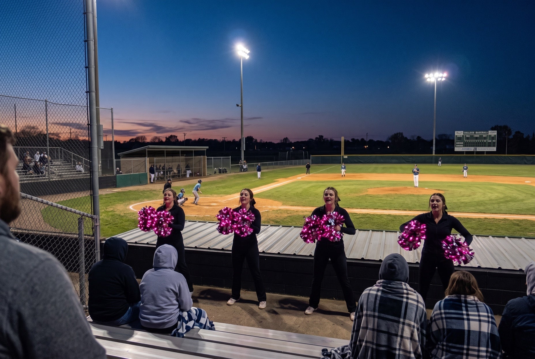 Light up LED pom poms glowing pink at a college baseball game at dusk