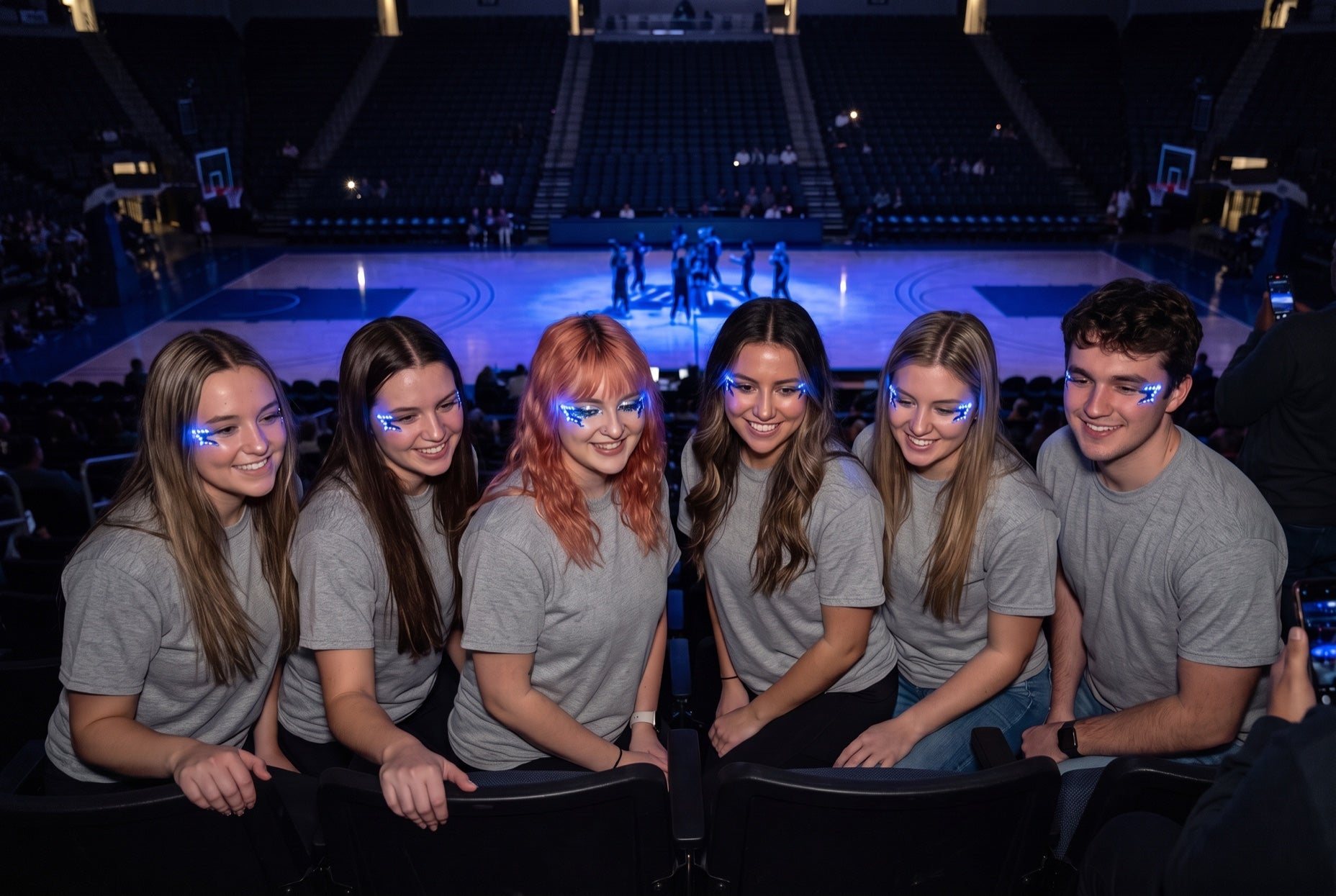 Clinic giveaway idea: six adults in plain gray tees wear blue LED face stickers by the eyes in dark arena stands