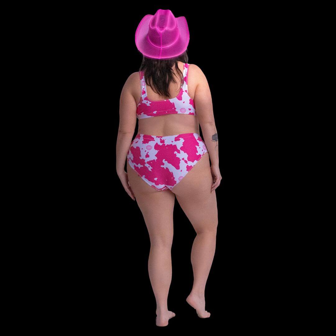 Woman wearing pink cowboy hat modeling stylish cow print bikini at beach music festival combining country western fashion with comfortable swimwear for summer vacation outfits and events