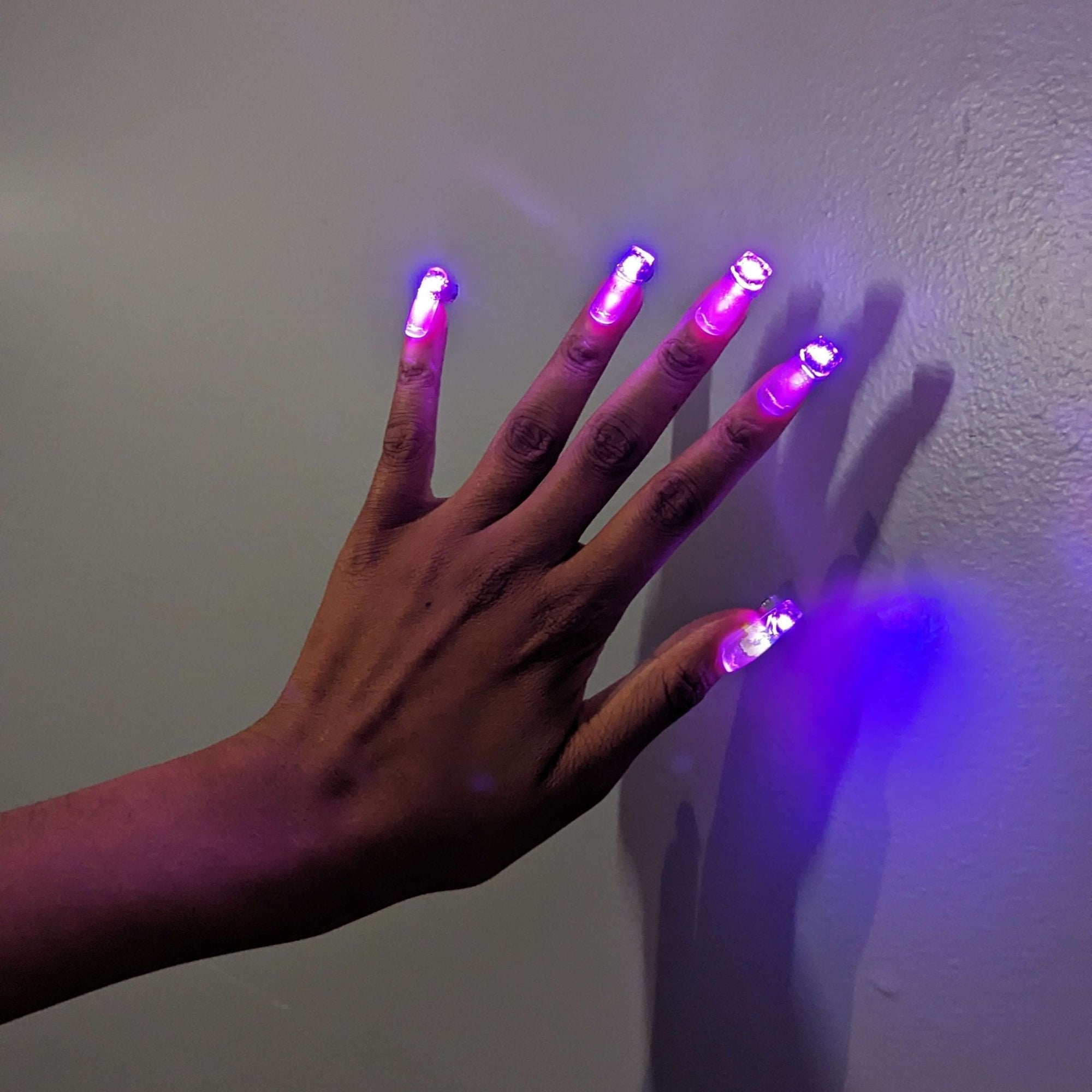 Hand displaying pink and purple LED press-on nails - Wireless light up nail extensions for Megan Thee Stallion concerts, club nights, and fashion-forward everyday looks