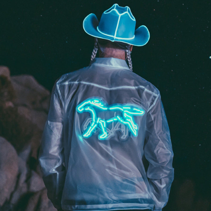 Man from behind at night in a clear water-resistant jacket with a glowing blue animated running horse on the back, a Neon Cowboys LED horse jacket and light up jacket led costume for space cowboy parties, festival stagewear, raves and motorcycle night riding, Neon Cowboys
