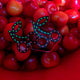 Bright red LED cherry stickers displayed on actual cherries - Creative product showcase of illuminated fruit-shaped facial jewelry for food-themed parties, summer festivals, and fruit fashion trends