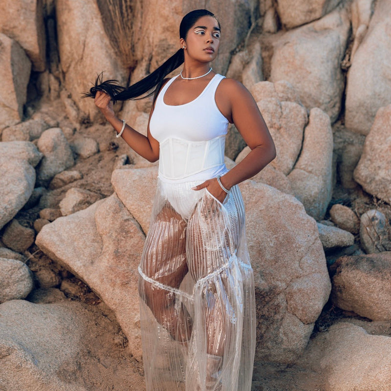 Model wears Neon Cowboys clear pleated transparent TPU pants over a white bodysuit and corset on desert rocks, light up rave outfit festival stagewear for go-go dancers and showgirls, perfect for festival fashion, music events and summer rave outfits, Neon Cowboys
