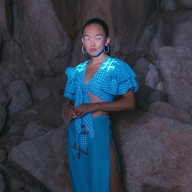 Model in a Neon Cowboys blue gingham tie front top that glows, styled with denim at night, light up western festival top for raves, country concerts, music festivals and disco cowgirl looks, Neon Cowboys