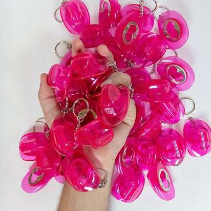 Handful of mini pink cowboy hat bottle opener keychains in bulk quantity perfect for festival group accessories and bachelorette party favors and corporate event gifts