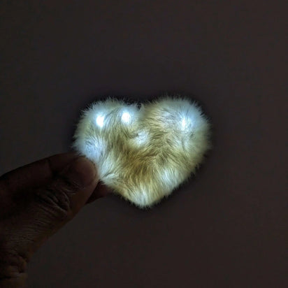 White LED heart fuzzy hair clip held in hand - Illuminated kawaii hair accessory for weddings, winter formals, glow parties, and everyday fashion enhancement