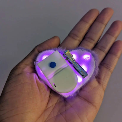 LED heart fuzzy hair clip with controller in hand - Detailed view showing illumination controls for kawaii hair accessories that brighten dance events, music festivals, and nighttime gatherings