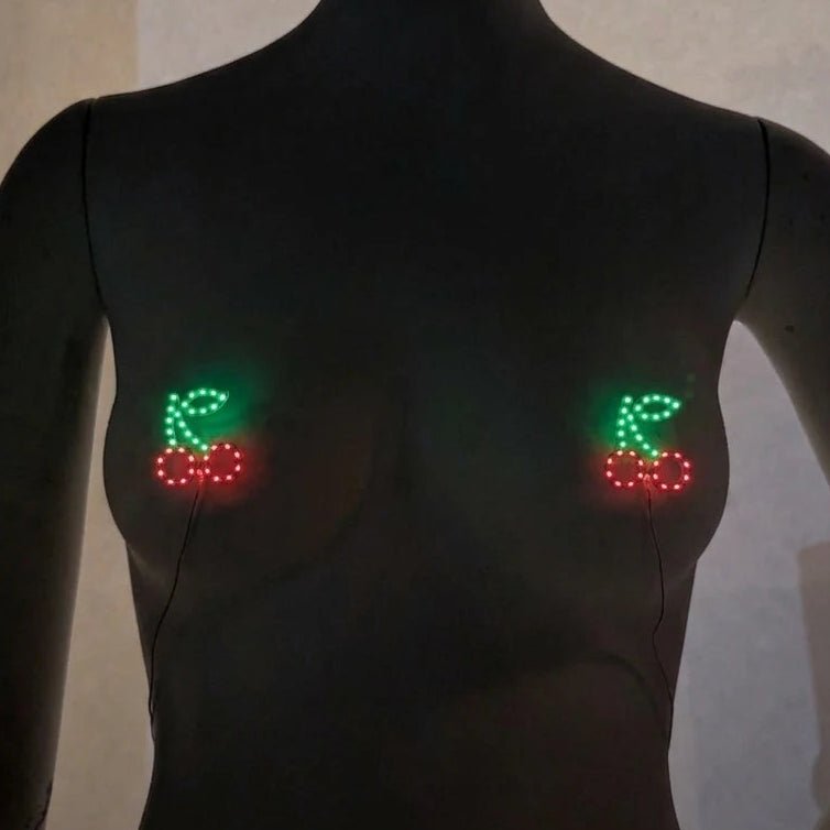 Glowing red and green LED cherry pasties on a mannequin — light-up cherry nipple covers by Neon Cowboys