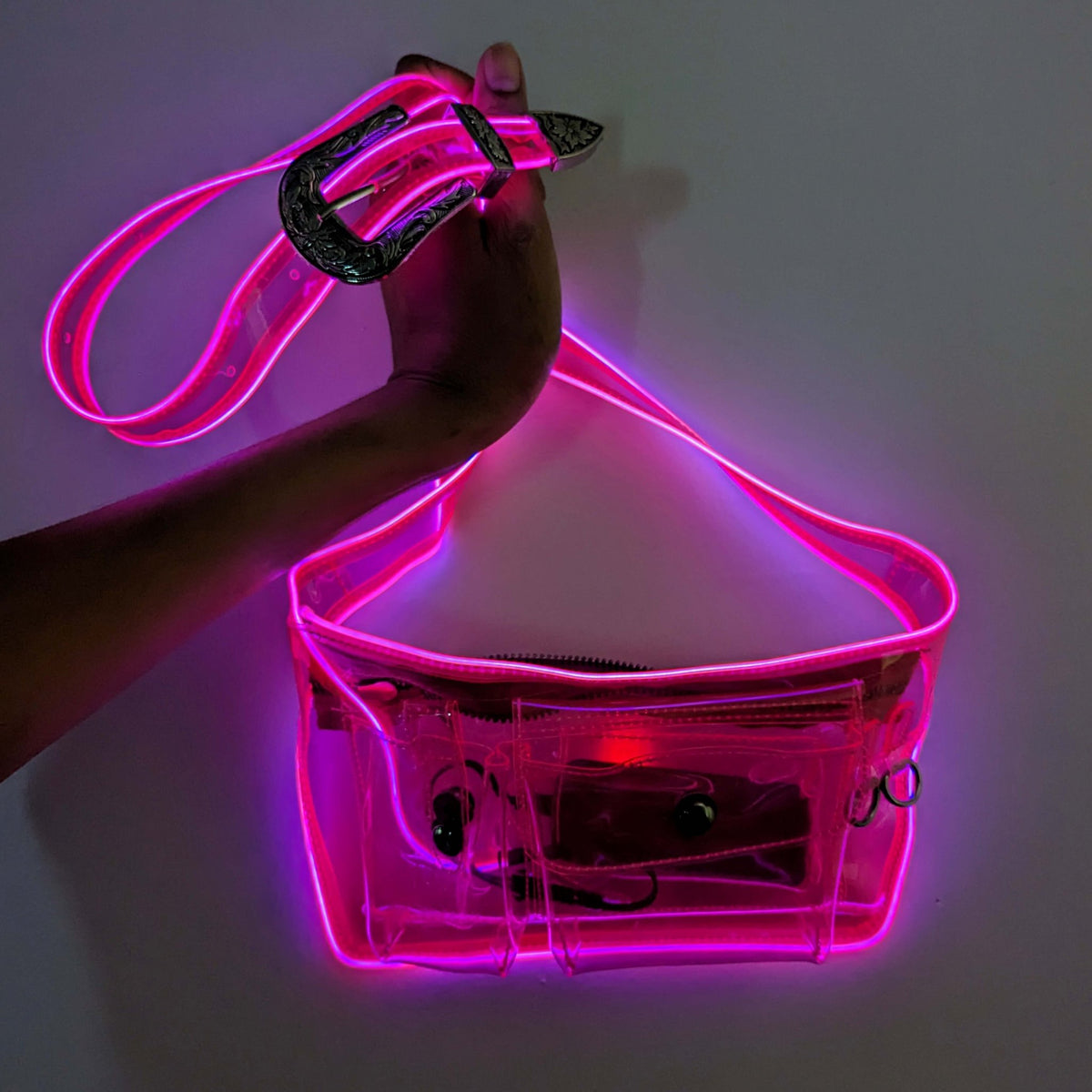 Hand holding glowing pink fanny pack showing transparent stadium approved design ideal for concerts and security-compliant venue entry