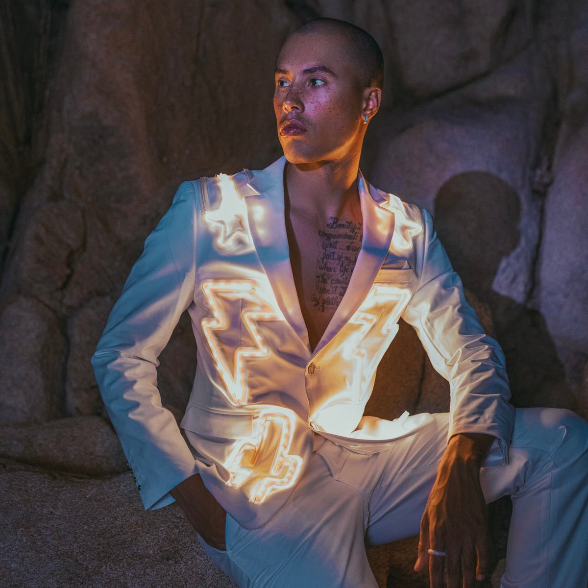 Model wearing holographic silver LED nudie suit jacket in natural lighting showing daytime styling options for festival fashion statement pieces and avant-garde streetwear