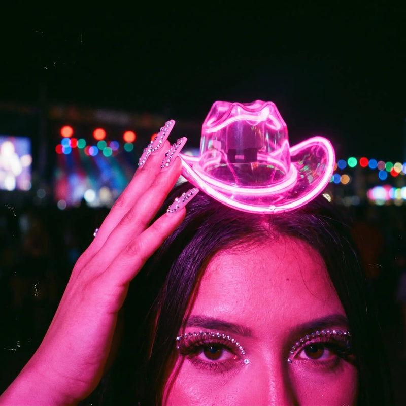 Woman wearing a pink glowing LED light-up mini cowboy hat on a headband at a night music festival, a neon cowgirl hat and space cowgirl accessory for raves, music festivals, bachelorette parties and disco cowgirl looks, Neon Cowboys