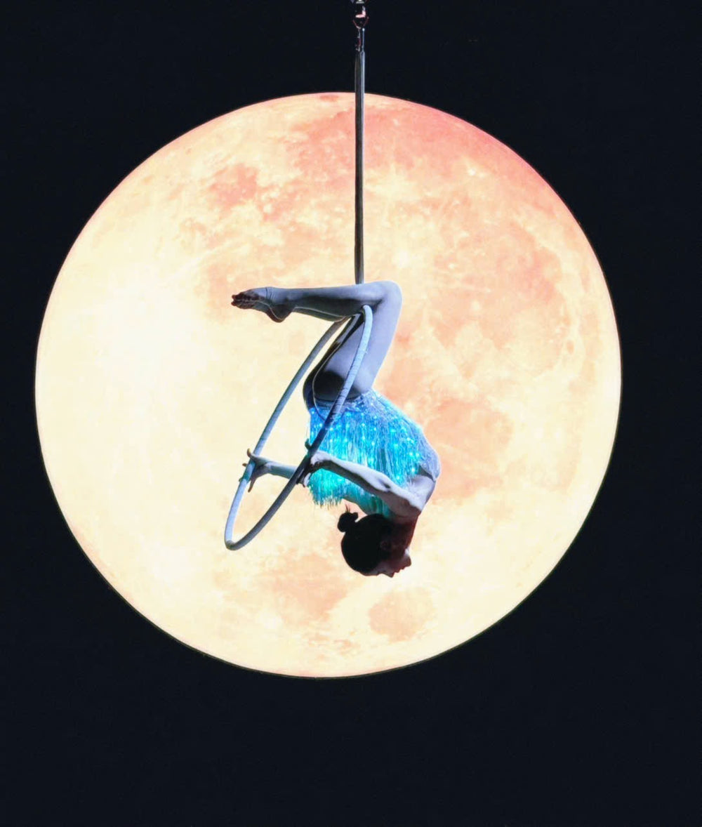 Aerial lyra performer inverted in glowing LED fringe