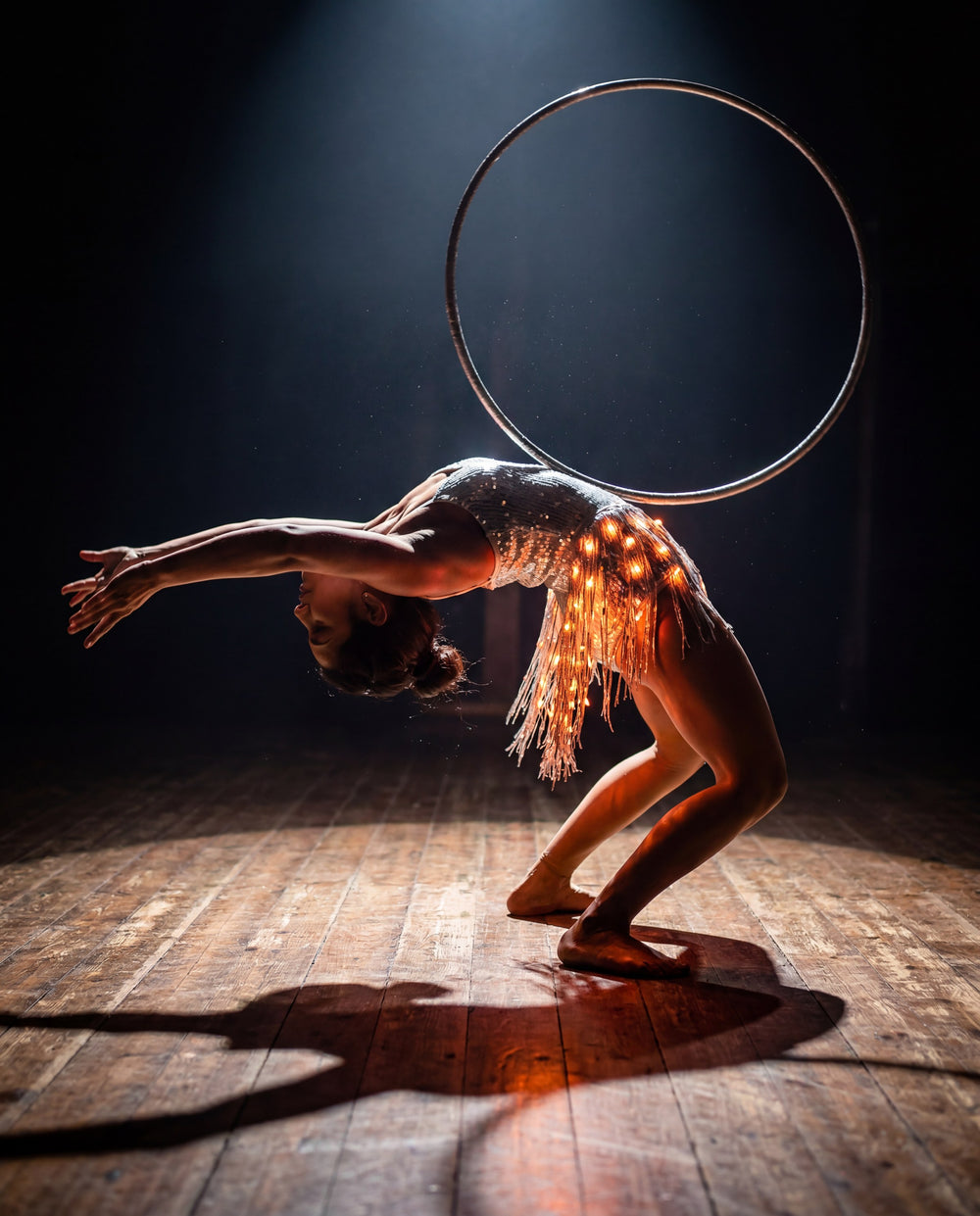 Hoop performer in glowing Neon Cowboys LED fringe stagewear under a spotlight