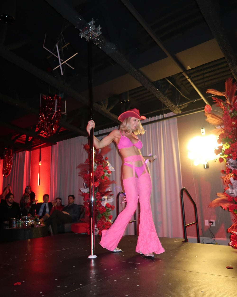 Pole dancer in a pink Neon Cowboys LED light-up cowboy hat and lace flares