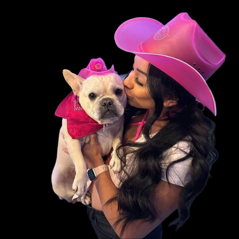 Woman in a pink glowing LED cowboy hat kisses a white French Bulldog wearing a matching mini light up cowboy hat, coordinating illuminated western headwear and glow in the dark cowboy hats for pet photoshoots, costume parties, birthdays, and viral social media content, Neon Cowboys PAWdner pet hat pack, Neon Cowboys