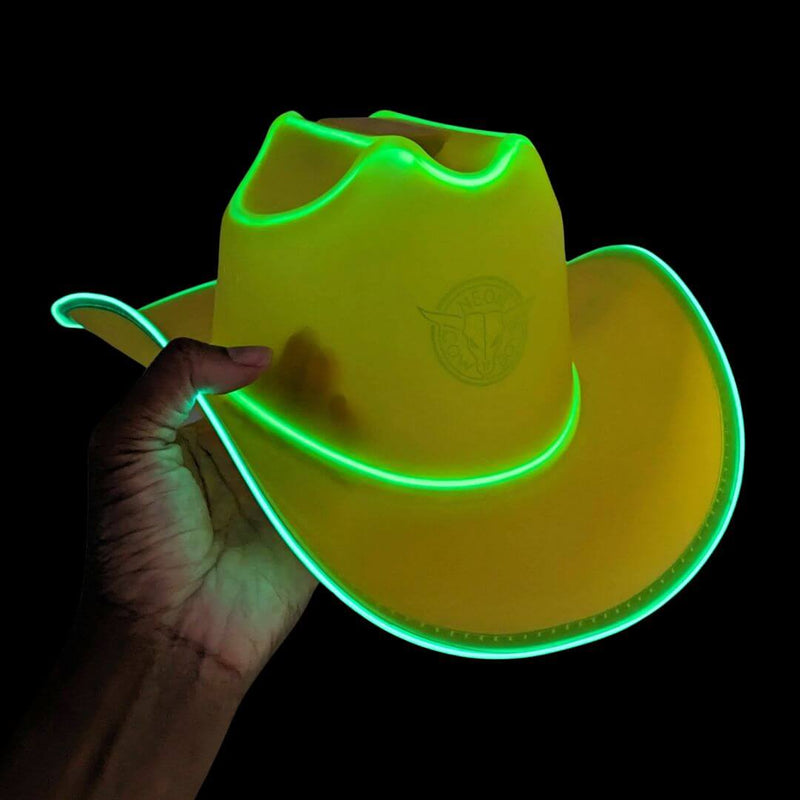 Hand holding an acid yellow limited edition cowboy hat with green-glowing LED trim on black, a vibrant neon cowboy hat and glow cowboy hat, western headwear glowing in the dark for music festivals, raves and country concerts, Neon Cowboys