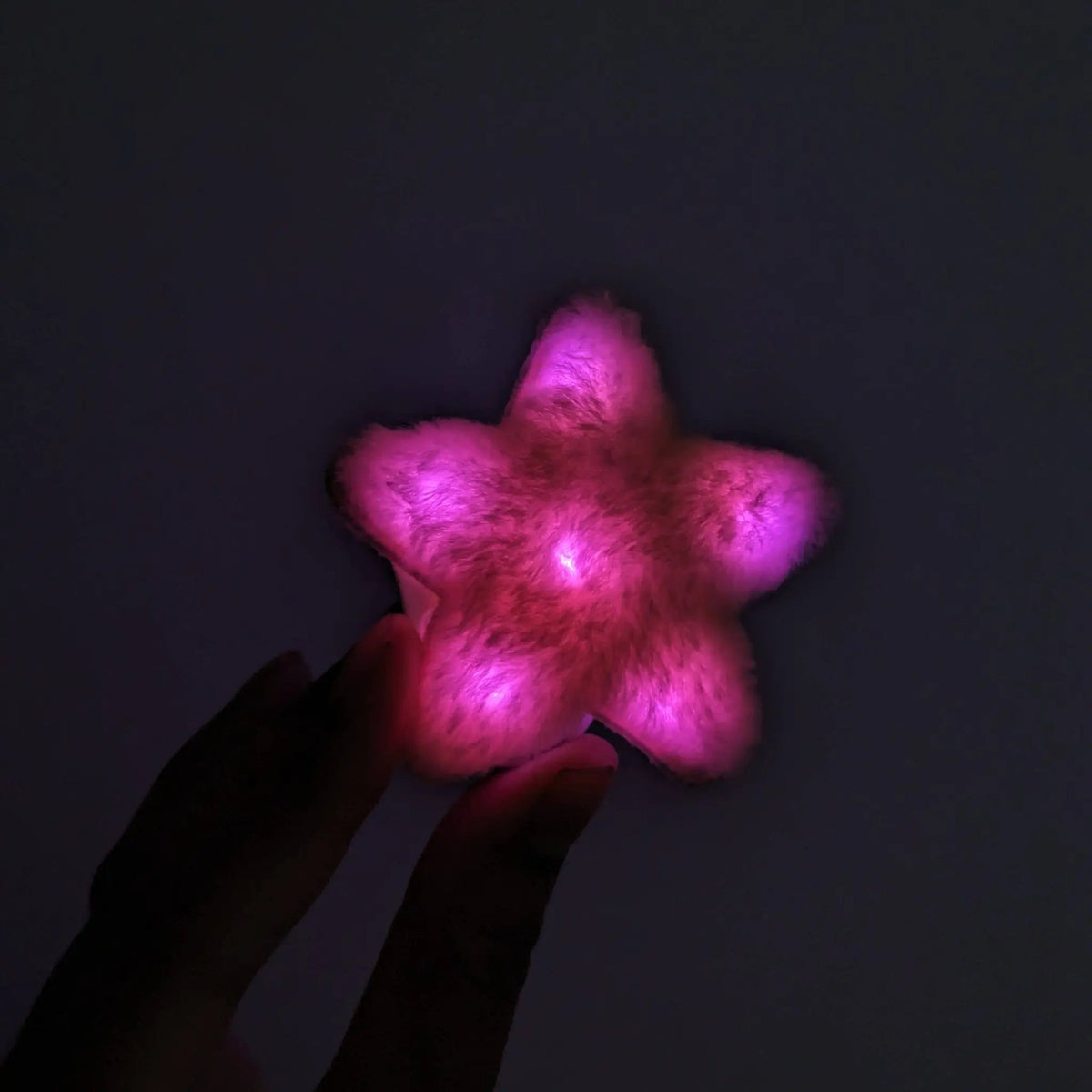 Pink LED star fuzzy hair clip held in hand - Vibrant illuminated star-shaped hair accessory for princess parties, Valentine's Day events, sweet sixteen celebrations, and girl gang outfits