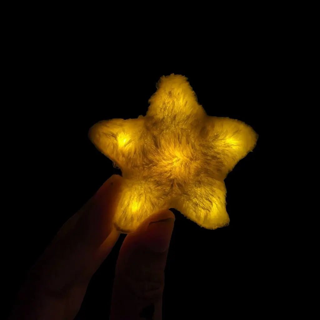 Gold LED star fuzzy hair clip held in hand - Yellow illuminated star-shaped hair accessory for celestial costumes, golden birthday themes, awards ceremonies, and astronomical celebrations