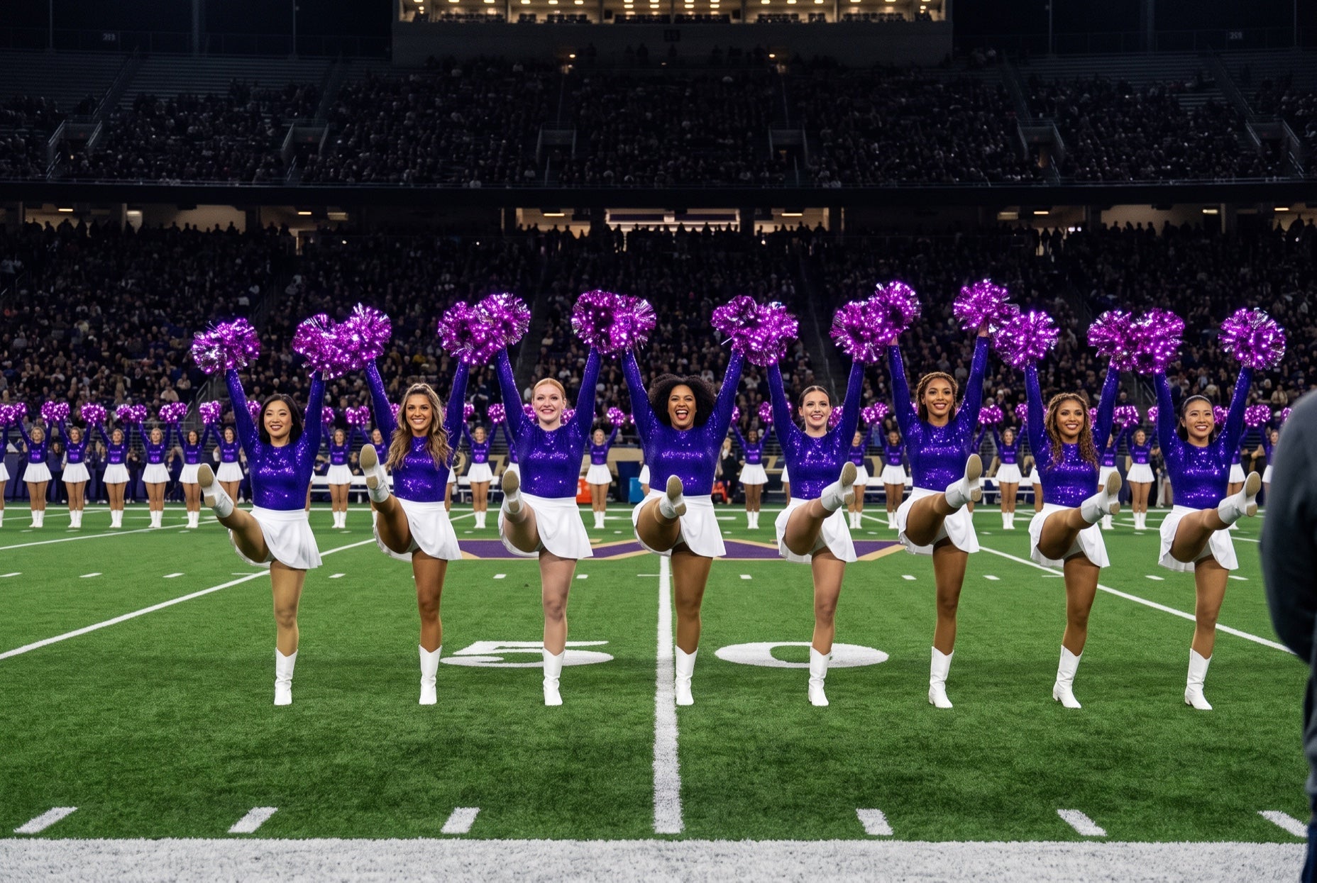 Light up LED purple pom poms glowing on a college drill team kick line in purple and white on the field at night