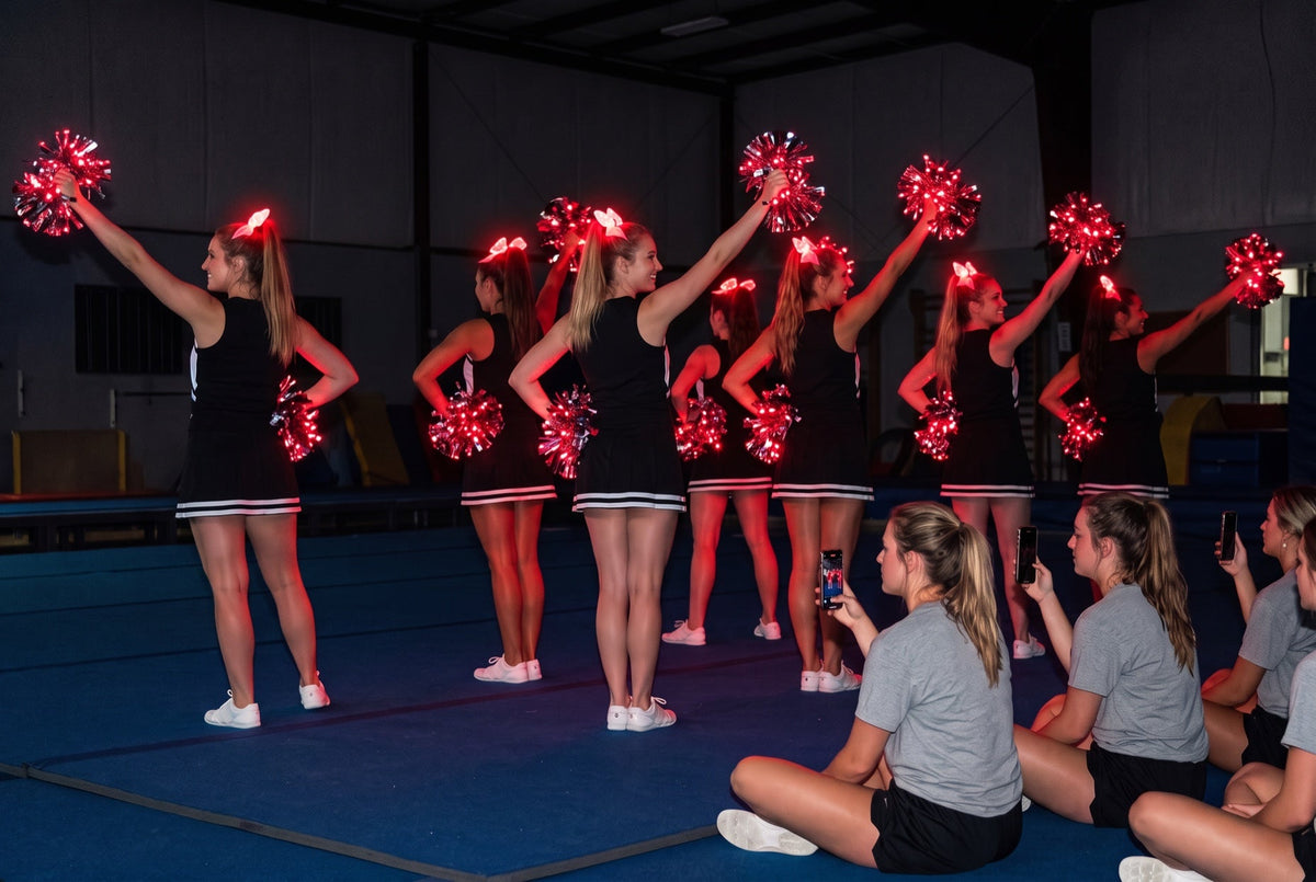 How to run a cheer clinic: squad in black with red LED pom poms and glowing bows on high ponytails as attendees film