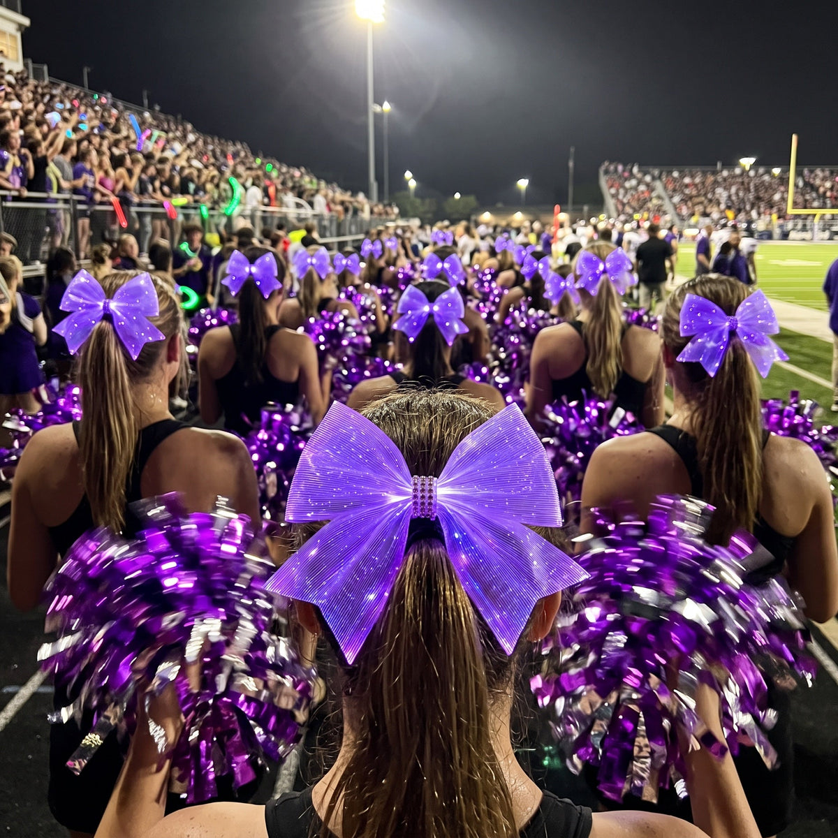 Light-up cheer bows for teams: LED bows glowing purple on a dance team's high ponytails with pom poms at a night game