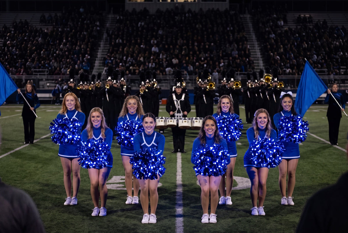 Light up LED royal blue pom poms glowing on a university pom line in front of the marching band and drumline at night