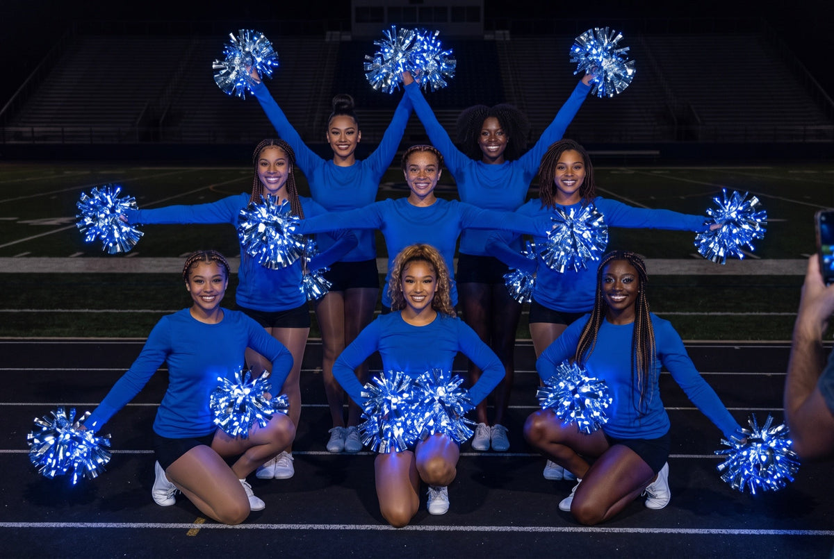Technique Tuesday pom drill: eight dancers in blue hit a three-level pose with blue LED pom poms on a dark stadium track