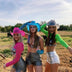 Three women wearing LED cowboy hats in outdoor country setting - Pink and green illuminated western headwear for farm events, country fairs, outdoor weddings, summer barbecues, and hayride parties