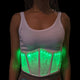 Front view of woman wearing bright green programmable LED corset with changing light patterns over white tank top, perfect for glow parties