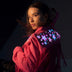 Animated Starlight Jacket with Fringe, woman looking over her shoulder in a pink fringe jacket with glowing LED light-up stars on the back, an led fringe sequin dress alternative and light up jacket for go-go dancers, raves, music festivals and Coachella, Neon Cowboys