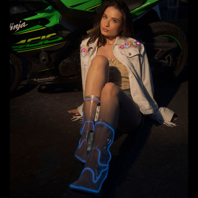 Animated Starlight Jacket with Fringe, woman seated by a green Kawasaki Ninja in a white LED star fringe jacket and blue light-up boots, an led fringe jacket and disco cowgirl stagewear for rave performers, music festivals and EDM concerts, Neon Cowboys