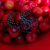 Bright red LED cherry stickers displayed on actual cherries - Creative product showcase of illuminated fruit-shaped facial jewelry for food-themed parties, summer festivals, and fruit fashion trends