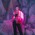 Woman wearing vibrant pink LED fringe jacket at night creating eye-catching movement for music festivals EDM concerts and nightclub parties
