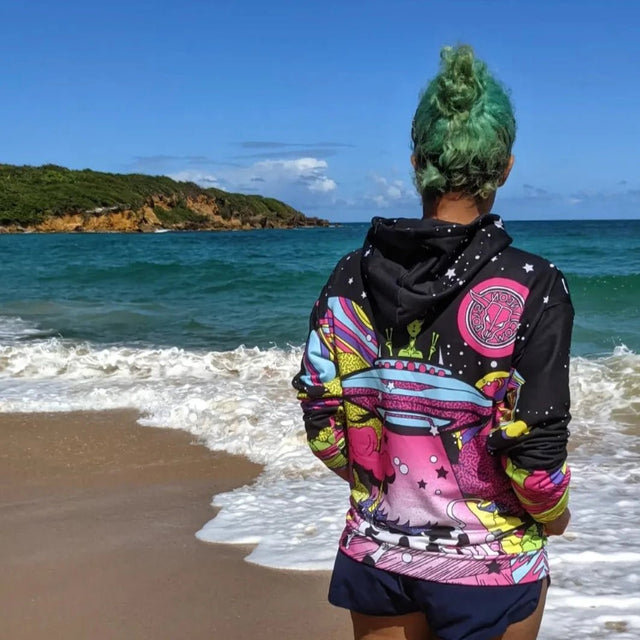 Person wearing Day at the Farm alien cow hoodie at beach party showcasing versatile festival clothing for outdoor summer events and coastal celebrations