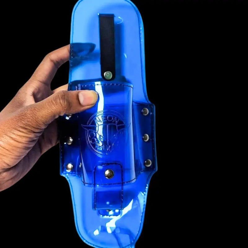 Hand holding a translucent blue PVC Neon Cowboys festival drink holster with embossed logo against a black background, a hands-free clip-on beer holster that securely holds a 12oz bottle for concerts, music festivals, raves and outdoor tailgates, Neon Cowboys