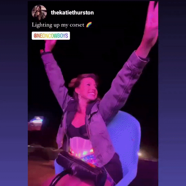 Female DJ wearing programmable LED corset in pink lighting while performing at nightclub rave party, showcasing light up stage fashion