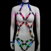 Color-changing LED body harness glowing in rainbow colors — a full-body light-up cage harness with glossy black straps and silver O-rings, for raves, festivals and performers.