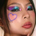Woman with rainbow makeup and heart LED sticker - Colorful festival-ready look combining illuminated facial jewelry for Pride events, EDM festivals, artistic photoshoots, and theatrical performances