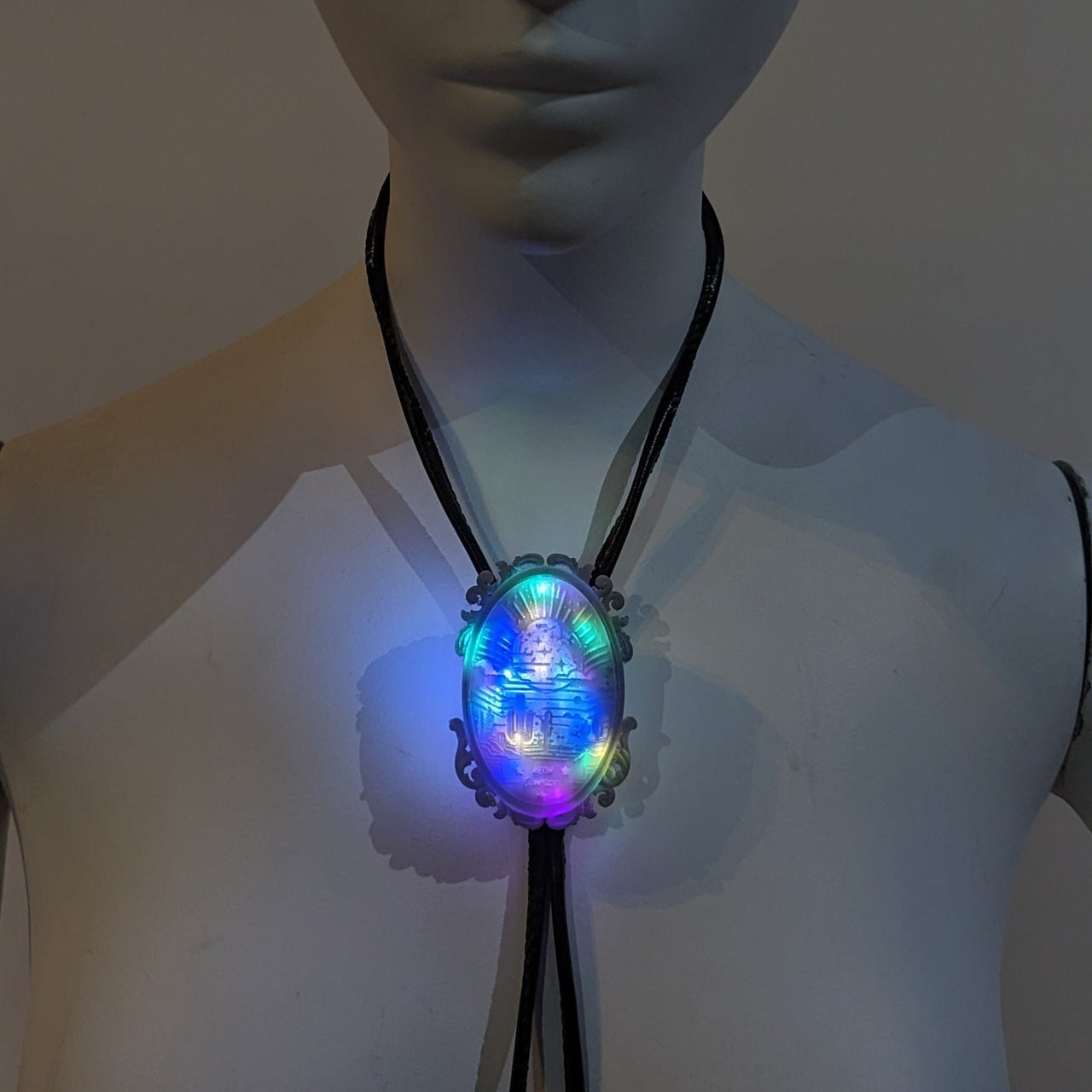 LED bolo tie worn on mannequin showing placement - Illuminated multicolored western accessory for music festivals, country concerts, rodeo events, and futuristic cowboy costumes