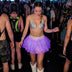 Woman in a purple glowing Neon Cowboys LED 3 Layer Tiered Skirt and holographic top with white cowboy boots in a festival crowd, a light up dress and led rave outfit stagewear for go-go dancers, showgirls and rave performers, a disco cowgirl festival outfit for raves, EDM concerts and Pride, Neon Cowboys