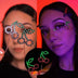 Cherry LED light-up face stickers held up and worn glowing green and red under studio lighting, led face jewelry and led face gems with festival makeup for raves, music festivals, EDM concerts and summer parties, Neon Cowboys