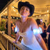 Woman in a black cowboy hat wearing a Neon Cowboys LED Fairytale Dream Dress with white glowing puff sleeves at a patio party, a light up dress and led rave outfit stagewear for showgirls, drag queens and cabaret performers, a disco cowgirl festival outfit for raves and bachelorette parties, Neon Cowboys