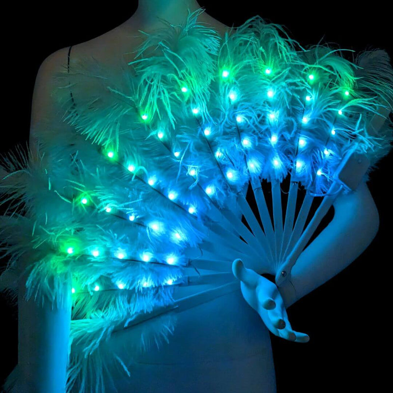 White LED feather fan glowing teal and blue held by a mannequin in the dark, a color-changing remote-controlled light up feather fan for burlesque performers, drag artists and cabaret stagewear, perfect for raves, EDM festivals, burlesque performances and multi-day music events, Neon Cowboys