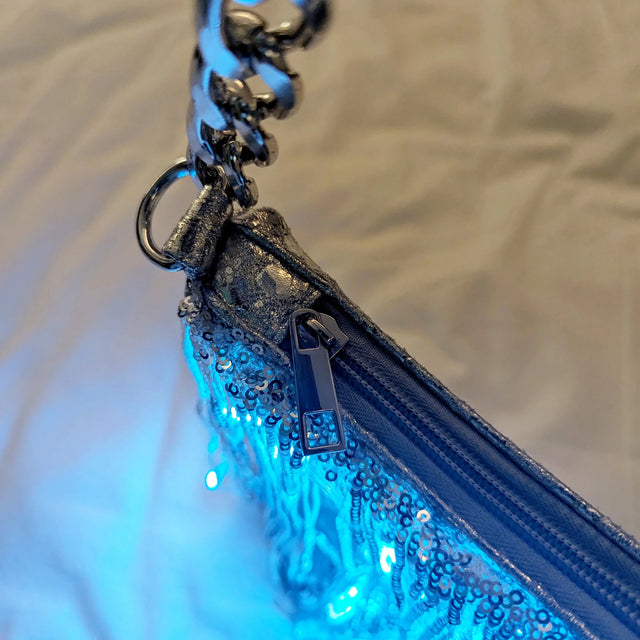 Close-up of a silver LED fringe purse zipper and chain strap glowing blue, a glowing light up purse and star-purse style bag perfect for raves, EDM concerts, festivals and nights out, Neon Cowboys