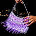 Hand holding a silver LED fringe purse glowing purple against a city skyline at night, a light up purse and light up fanny pack alternative, glowing star purse and clear-bag concert bag perfect for raves, EDM concerts, festivals and nights out, Neon Cowboys