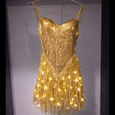 LED Fringe Sequin Dress by Neon Cowboys, a gold light up sequin fringe dress with the fringe glowing warm gold on a hanger, this led fringe sequin dress, led dress and light up dress with a led bodysuit base is space cowgirl and showgirl, go-go dancer and drag stagewear for raves, EDM concerts, festivals and bachelorette parties, Neon Cowboys