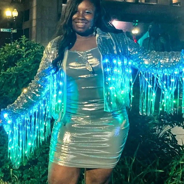 Woman in light blue LED sequin fringe jacket outdoors at night - Vibrant illuminated sequin apparel creating dramatic effect for festival grounds, outdoor concerts, and nighttime celebrations