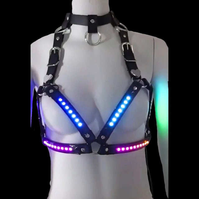LED Halter Harness glowing in blue and purple — a color-changing light-up triangle halter bralette with black patent straps and silver O-rings, for raves, festivals and performers.