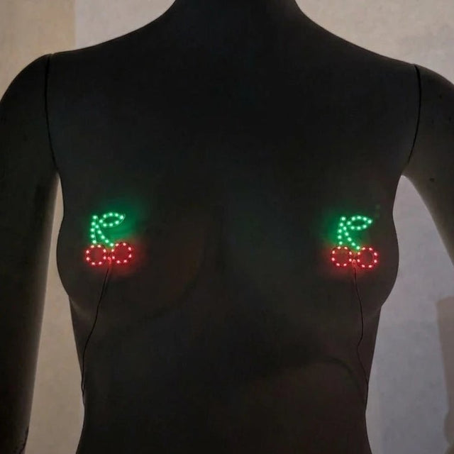 Glowing red and green LED cherry pasties on a mannequin — light-up cherry nipple covers by Neon Cowboys