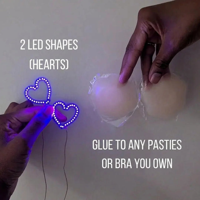 Two glowing purple LED heart shapes next to silicone pasties — light-up heart nipple covers you glue onto any pasties or bra